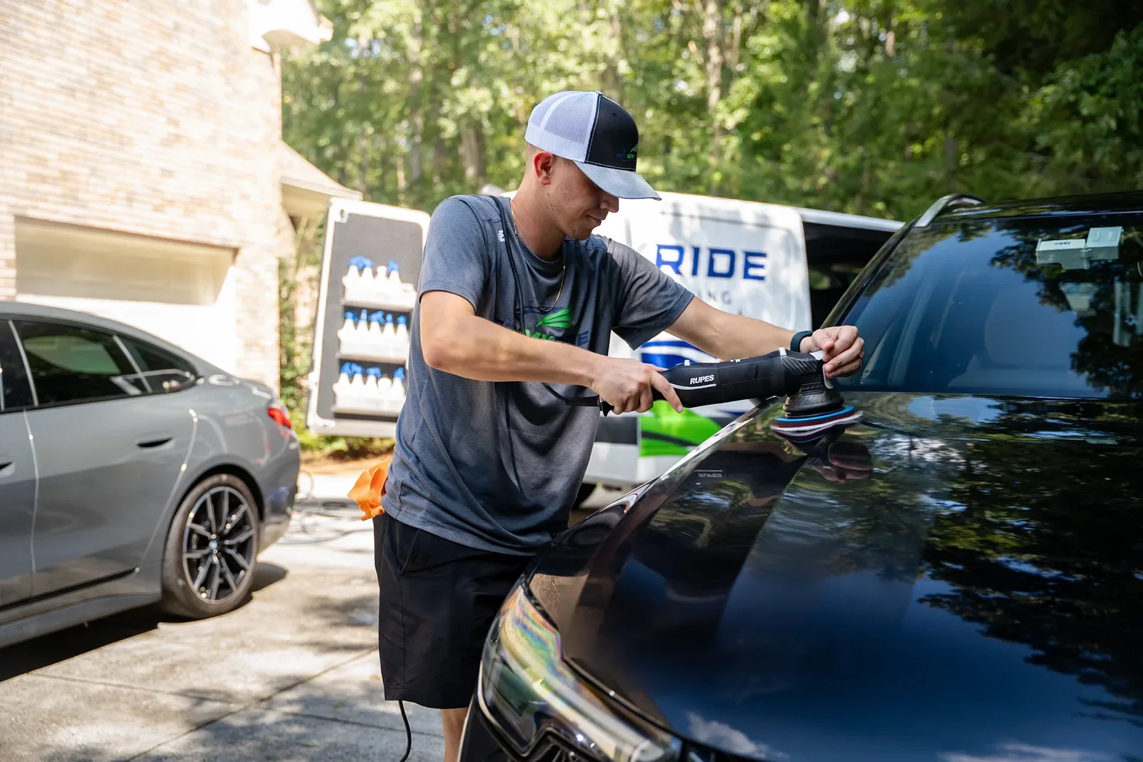 FlyMyRide technician polishing a vehicle beside the branded service van