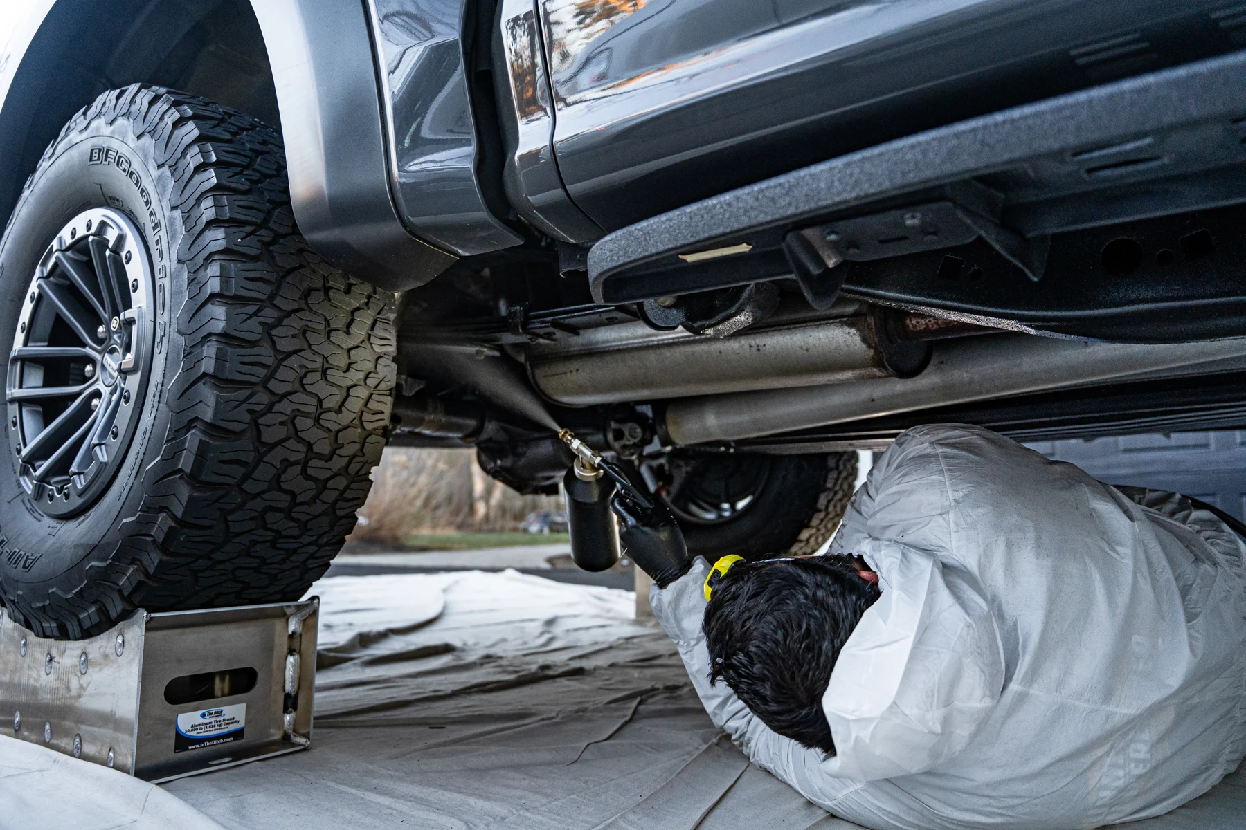 UnderCover technician applying undercoating beneath a raised pickup at the customer’s location